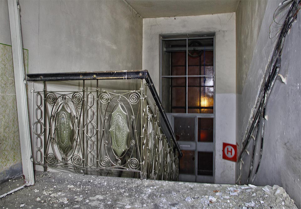 Historické schodiště sousedí s relativně moderním výtahem vyčnívajícím do dvora domu. Ten nahradil v 70. letech původní výtah se stěnou šachty zdobenou barevnou secesní vitráží z roku 1909.