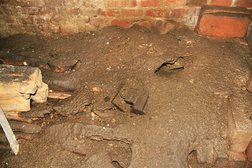 Po poslední havárii pohřbilo kanalizační bahno některé části sklepa. Nejrůznější předměty se noří z měkké krusty jako paláce z popela v Pompejích.